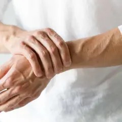 Mężczyzna masuje prawą rękę, odczuwając drętwienie.