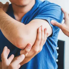 Lekarz bada ramię pacjenta, który odczuwa ból. Może to być jeden z objawów rabdomiolizy.