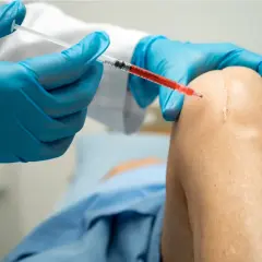 Lekarz podaje zastrzyki z kwasu hialuronowego w kolano NFZ, łagodząc ból i poprawiając ruchomość.