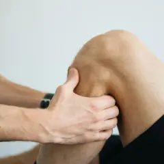 Fizjoterapeuta bada kolano pacjenta, podejrzewając naderwanie więzadła.