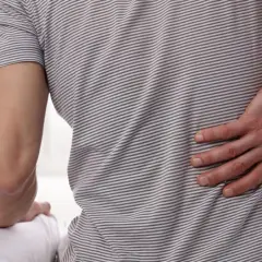 Mężczyzna z bólem w dolnej części pleców, wskazującym na zaburzenia splotu lędźwiowo-krzyżowego.