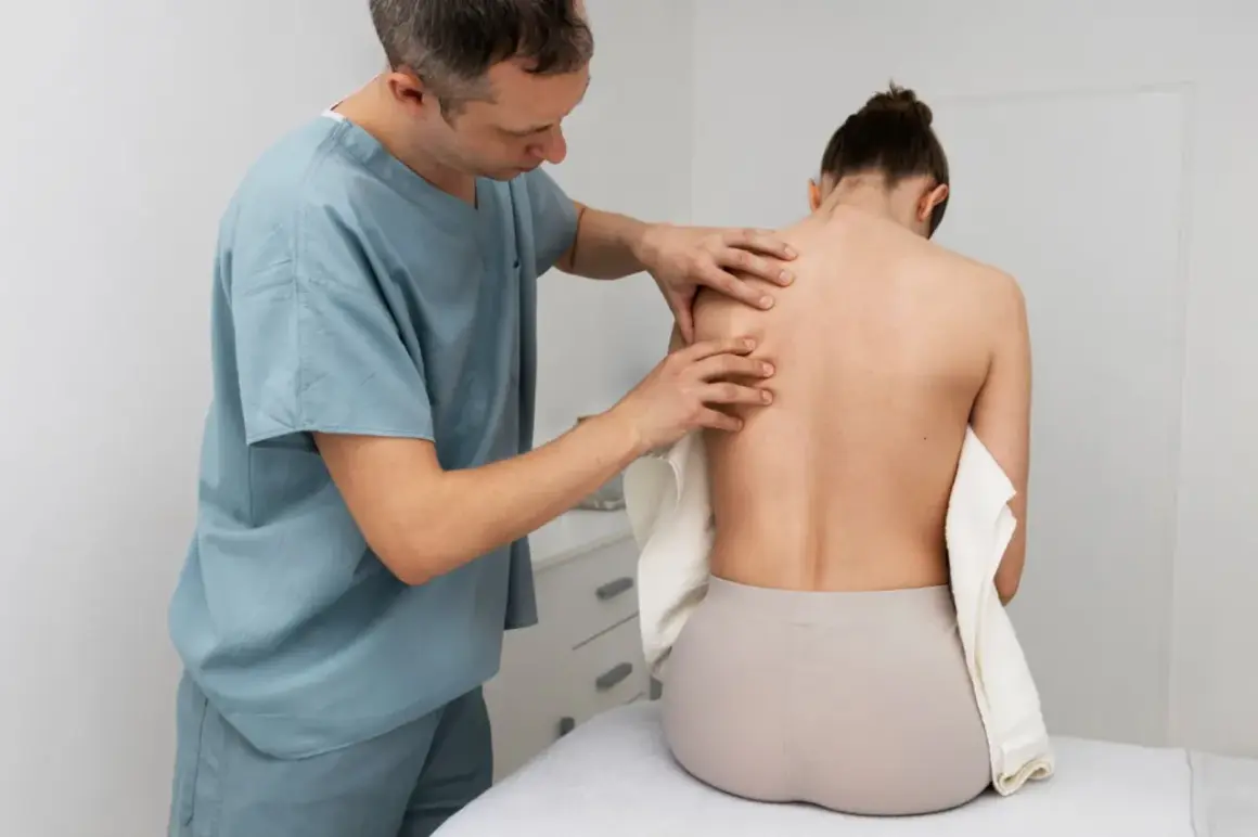 Fizjoterapeuta bada plecy pacjentki, oceniając bliznę po operacji skoliozy.