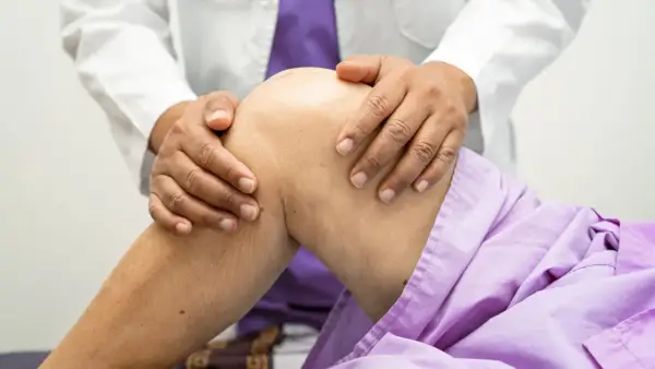 Lekarz bada kolano pacjenta, podejrzewając zerwane ACL. Wyniki rezonansu pomogą w diagnozie.