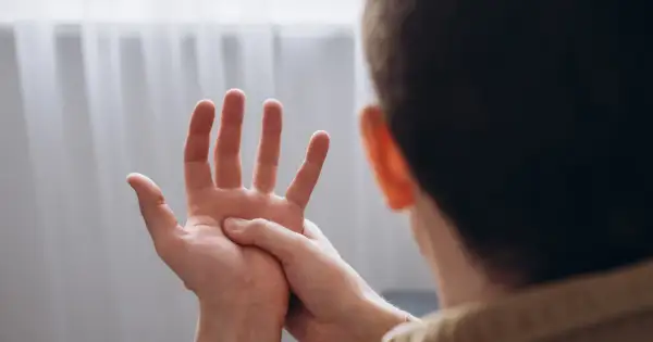 Mężczyzna masuje dłoń, odczuwając drętwienie rąk.
