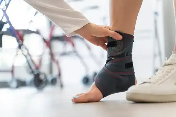 Rehabilitacja po urazie: specjalista zakłada stabilizator na staw skokowy, przygotowując pacjenta do badania rezonansem.