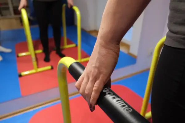 Rehabilitacja po niedowładzie nóg: ćwiczenia na poręczach. Dłoń trzymająca uchwyt.